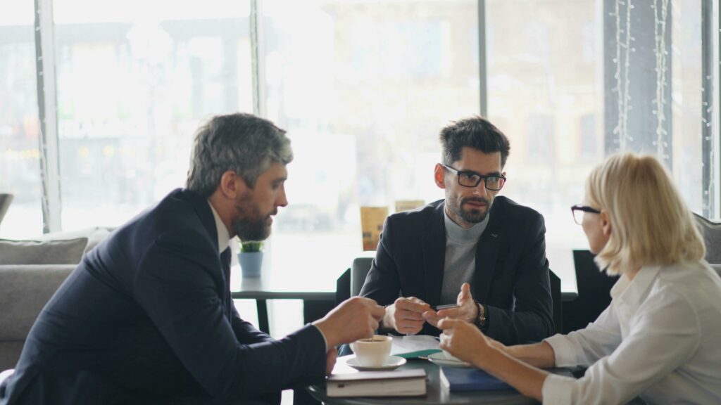 Réunion de travail entre trois personnes autour d'une table.